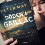 Kvinna med glasögon läser boken Döden i Gaillac av Peter May